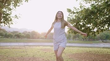 Young happy woman enjoys running through in park, flip hair beautiful moment of nature and sunlight as background, freedom concept, young wild and free, self isolation, different world, tropical video