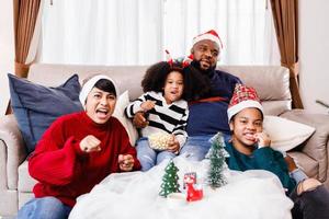 la familia feliz se divierte sentada en el sofá de casa. alegre familia joven con niños riendo. familia afroamericana foto