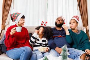 la familia feliz se divierte sentada en el sofá de casa. alegre familia joven con niños riendo. familia afroamericana foto