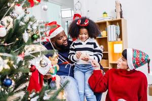 African American family help decorate the Christmas tree at home. Merry Christmas. photo