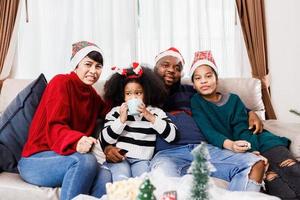 la familia feliz se divierte sentada en el sofá de casa. alegre familia joven con niños riendo. familia afroamericana