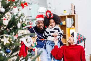 African American family help decorate the Christmas tree at home. Merry Christmas. photo