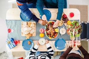 la vista superior de la familia feliz es cenar en casa. celebración vacaciones unión cerca del árbol de navidad. foto