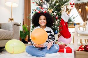 la familia afroamericana ayuda a decorar el árbol de navidad en casa. Feliz Navidad. foto