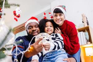 African American family help decorate the Christmas tree at home. Merry Christmas. photo