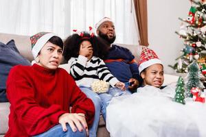 la familia feliz se divierte sentada en el sofá de casa. alegre familia joven con niños riendo. familia afroamericana foto