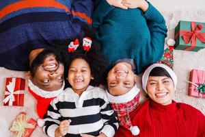 familia afroamericana en tema navideño. feliz familia afroamericana de cuatro personas que se unen en el suelo juntos. foto