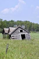 an abandoned farm building is slowly collapsing photo