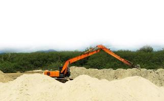 orange backhoe It is scooping up sand that blocks the river flowing into the sea so that ships can travel easily. photo