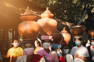 la tradición de ofrecer limosna a los monjes y la forma de vida del pueblo mon en colocar los utensilios sobre sus cabezas indígenas. foto