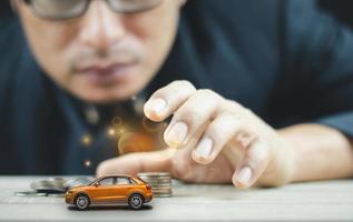 los hombres están usando sus manos para agarrar modelos de automóviles y monedas para ahorrar dinero para el automóvil de sus sueños. foto