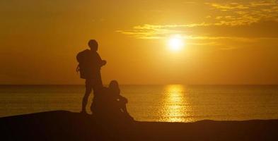 A panoramic view of the silhouette of men and women looking at the serene sunset . photo