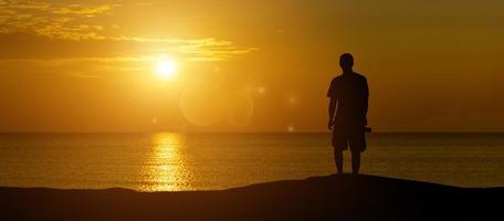 A panoramic view of a man silhouette holding a camera looking at a quiet sunset . photo