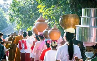 la tradición de ofrecer limosna a los monjes y la forma de vida del pueblo mon al colocar los utensilios sobre sus cabezas indígenas en la provincia de ratchaburi. foto