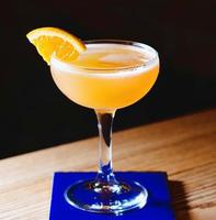 orange alcohol sour cocktail with citrus in elegant glass in the bar photo