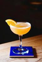 orange alcohol sour cocktail with citrus in elegant glass in the bar photo