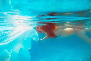 Portrait of smiling young beautiful red-haired girl in sunny day in open swimming pool in summer underwater photo