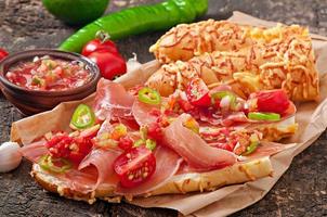 Salsa dip in bowl of bread and cheese sticks on wooden background photo