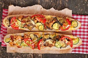 Big sandwich with roasted vegetables  with cheese and thyme on old wooden background photo