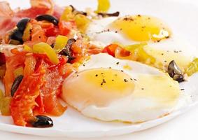 Breakfast - fried eggs with bacon, tomatoes, olives and slices of cheese photo