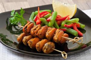 Fried mussels with onions on skewers c garnish of green beans and paprika photo