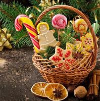 galletas de jengibre de navidad y piruletas en una canasta sobre fondo de madera vieja foto