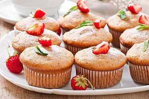 muffin de fresa en un plato blanco con una fresa fresca foto