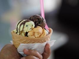 chocolate, té tailandés de naranja, helado de leche de coco en una taza de gofre crujiente en la mano de una mujer foto