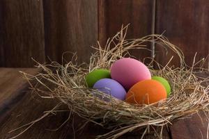 Easter eggs in nest on old wooden background photo