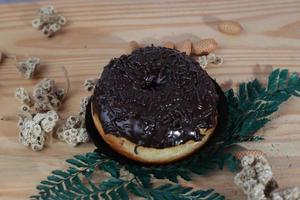 Brown donuts with sprinkles isolated on a wooden background photo