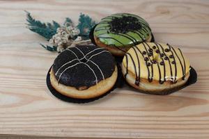 Brown donuts with sprinkles isolated on a wooden background photo