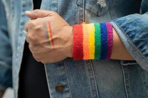 dama asiática con pulseras de la bandera del arco iris, símbolo del mes del orgullo lgbt celebran anualmente en junio las redes sociales de gays, lesbianas, bisexuales, transgénero, derechos humanos.