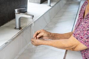 Asian senior or elderly old lady woman patient washing hand by soap and clean water for protect safety infection and kill Coronavirus Covid-19 virus, bacteria and germs. photo