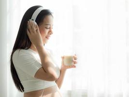 hermosas mujeres embarazadas escuchan música con auriculares y beben leche de soja foto