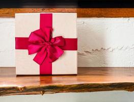 Gift box with red ribbon for happy holidays on wooden table photo
