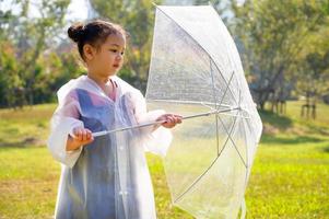 una niña estaba felizmente parada en un paraguas contra la lluvia foto