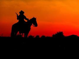 Western cowboys are sitting on horseback under the sun and preparing to use guns to protect themselves in a land that is not yet legal photo