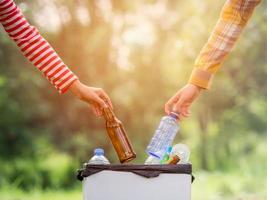 mujeres voluntarias recogen botellas de agua de plástico en el área del parque, de personas que se niegan a tirar la basura en una caja de papel para reciclar foto