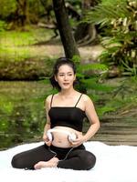 Beautiful pregnant women sit in the park, let the children in the belly listen to music from headphones photo