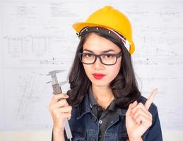 Female engineer holding a measuring instrument With a blueprint as a backdrop photo