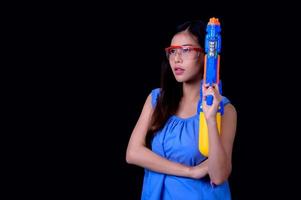 A beautiful Asian woman shows a gesture while holding a plastic water gun during the Songkran festival photo