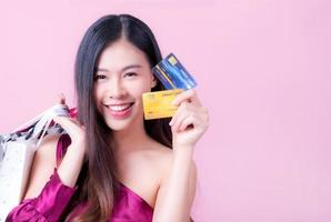 una hermosa mujer asiática está feliz y piensa que gastará muchas de sus tarjetas de crédito foto