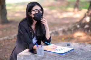 las mujeres de negocios asiáticas deben usar una máscara facial para prevenir la contaminación por polvo y prevenir la infección por virus, durante el brote del virus de la corona que tiene que trabajar en casa foto