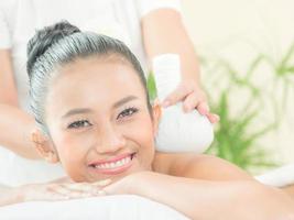 Young asian beautiful woman relaxing with compress thai herb in spa salon photo