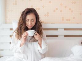 Beautiful woman is drinking coffee on the bed photo