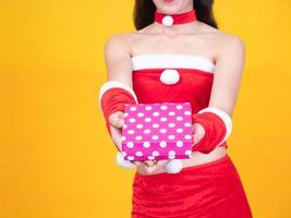 chica asiática con traje rojo de santa y caja de regalo en el día de la celebración foto