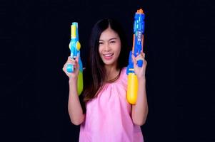 A beautiful Asian woman shows a gesture while holding a plastic water gun during the Songkran festival photo