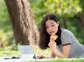 A beautiful Asian woman is happy as she uses her credit card to make purchases online via digital tablet photo