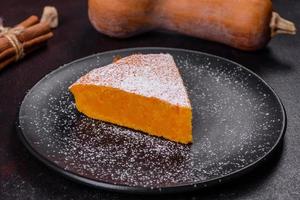 Pumpkin pie, tart made for Thanksgiving day with whipped cream on a black plate photo