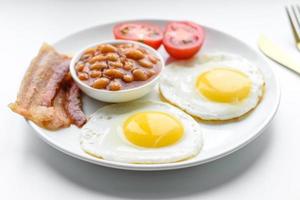 English breakfast with fried eggs, bacon, beans, tomatoes, spices and herbs photo